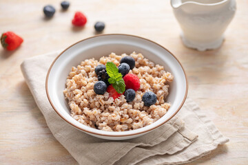 Pearl barley porridge with berries in a bowl on the table. Healthy breakfast