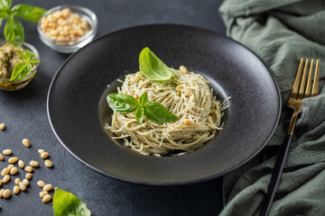 Spaghetti with pesto sauce and  cheese in plate on the table.