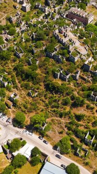 Vertical video. Kayakoy, Turkey. Aerial view of ancient ghost town ruins on hill slope, abandoned Greek village Levissi that inspired the book Birds Without Wings by Louis de Bernieres.. Aerial View,