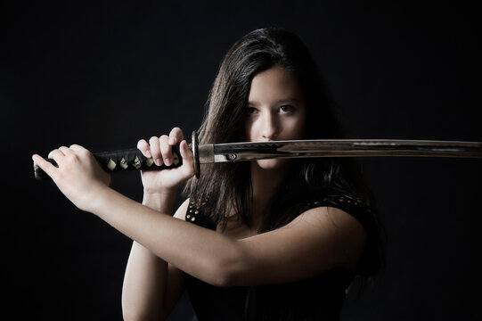 Portrait of serious young woman with katana sword and long hair