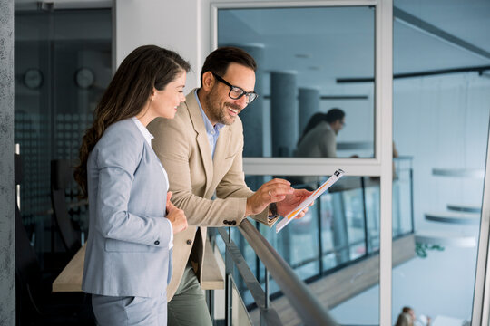 Business professionals discussing chart on tablet in modern office