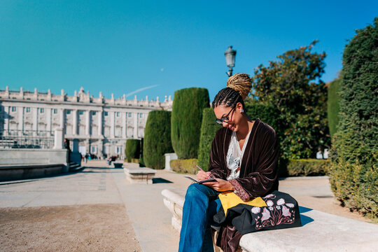 Tourist writing outdoors near Royal Palace of Madrid on a sunny day