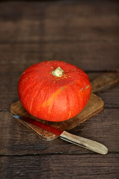 Organic pumpkin with knife on wooden board in rustic autumn setting