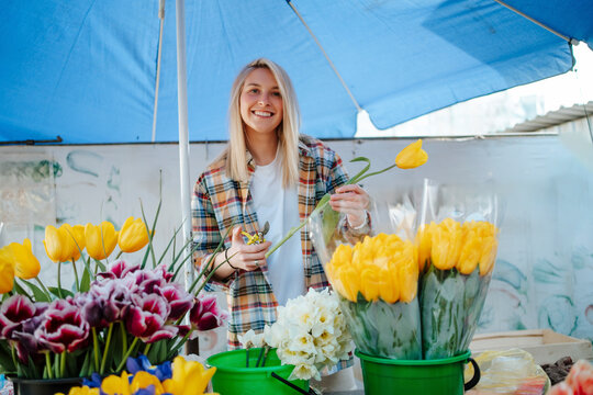 Smiling seller arranges tulips at outdoor flower market