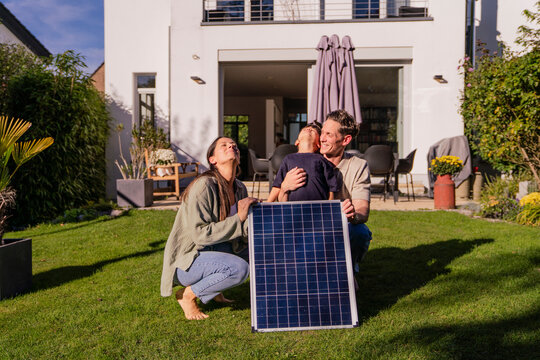 Family with solar panel in garden promoting sustainable energy at home