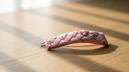 Embroidered pink hair clip with floral details rests on a wooden table in soft light