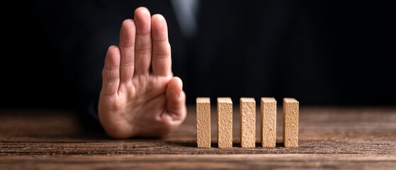 Preventing domino effect hand gesture signaling stopping action indoor setting close-up shot conceptual focus