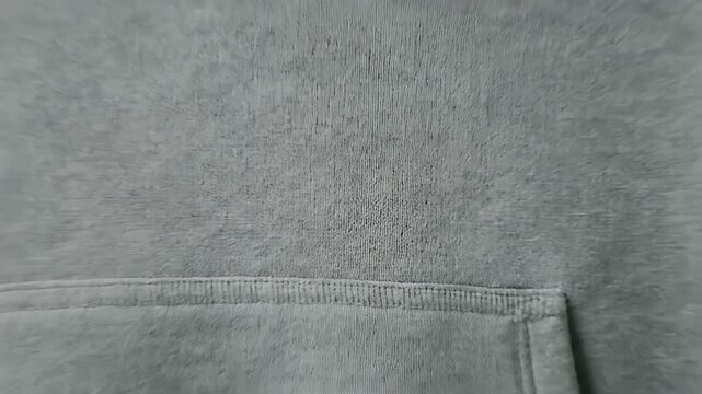 Close-up view of the soft texture and stitching detail on a grey hoodie pocket, showcasing the fabric's intricate pattern and comfortable feel.