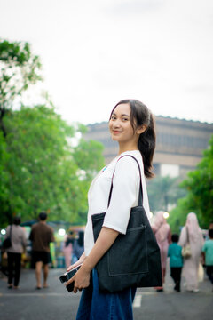 A cheerful Asian woman traveling alone and enjoying the atmosphere. Without any friends.