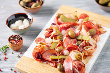 Meat charcuterie board with different sausage and bacon and pickled vegetables.