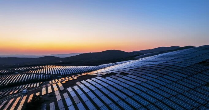 Aerial time-lapse of solar panel arrays on hills during twilight, capturing the blue hour glow and sustainable energy landscape.