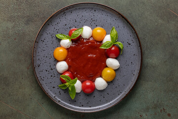 Caprese salad with tomato sauce on a plate on the table. Top view