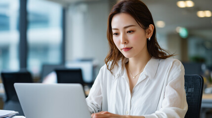 Japanese businesswoman working on laptop in modern office
