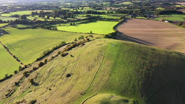 Cley Hill Camp univallate Iron Age hillfort near Warminster, Wiltshire. The 2 central Bronze Age bowl barrows seen from the south. Video fly back over barrows to old quarry