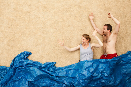 Playful young adults pretend to swim in studio beach scene with waves
