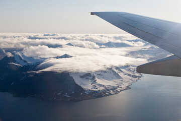 Aerial view of Spitsbergen Norway with airplane wing and snowy coast