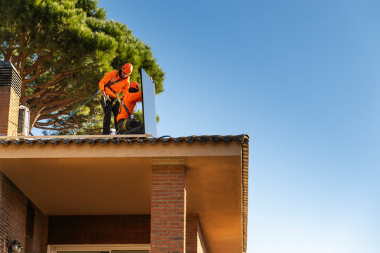 Technicians installing solar panel on roof working as a team outdoors