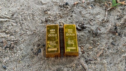 two pieces of gold bars and sandy soil background, suitable for wealth or investment, photo concept
