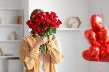 Young woman with red roses in dining room on Valentine's Day