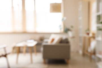 Fototapeta premium Blurred view of stylish living room with grey sofa, tables and window