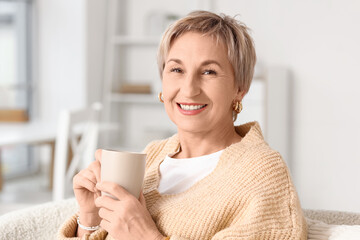 Blonde mature woman with short hair and cup of tea at home