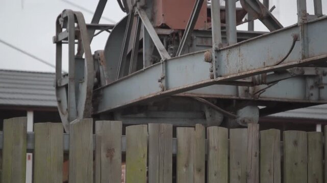 Old Rusty Industrial Crane Machinery Behind Fence