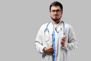 Portrait of handsome doctor in eyeglasses with badge on light background