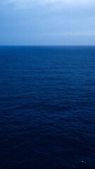 Obraz premium Vast expanse of deep blue ocean water under a cloudy sky