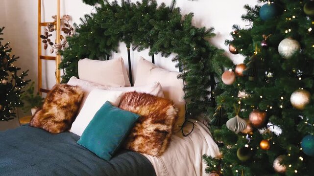 Festive bedroom with decorated Christmas trees and cozy pillows on bed