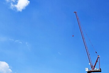 Large Red Construction Crane Against Blue Sky with White Clouds.