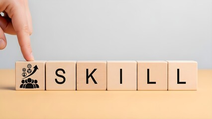 A hand placing a wooden block with a graph and people icon beside blocks spelling 'SKILL' on a table with a plain background.