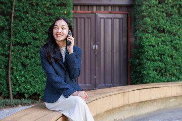 Fototapeta premium Young asian woman smiling having mobile phone conversation
