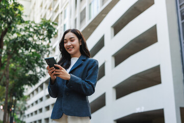 Young businesswoman smiling using phone in urban environment