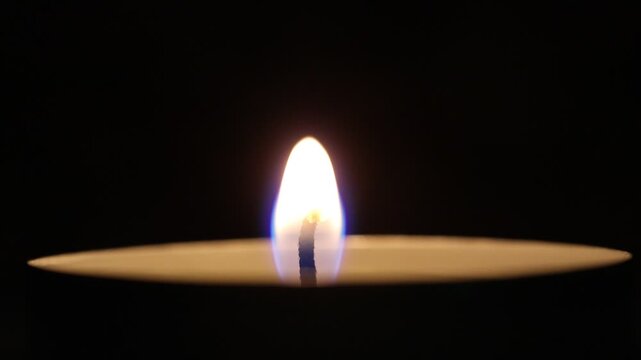 Macro shot of a candle flame flickering against a black background, 4K. - Powered by Adobe