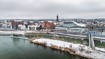 Snowy Venlo town waterfront near Maas river aerial drone view, winter cityscape with rooftops covered with snow, winter weather in Limburg, the Netherlands