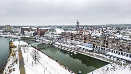 Snowy Venlo town waterfront near Maas river aerial drone view, winter cityscape with rooftops covered with snow, winter weather in Limburg, the Netherlands