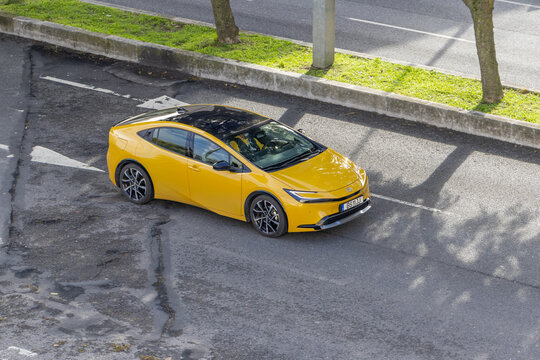 Yellow toyota prius hybrid electric car driving on road