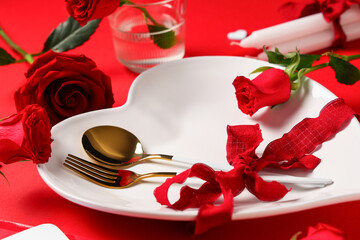 Table setting for Valentine's Day with rose flowers and candles on red background