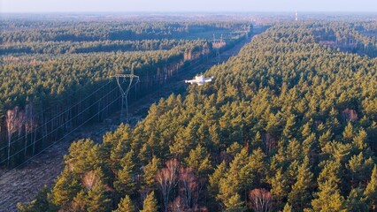Drone flight over a high-voltage electricity pylon at sunset.