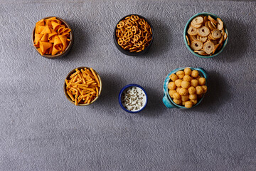Assorted snacks in pottery bowls on grey background