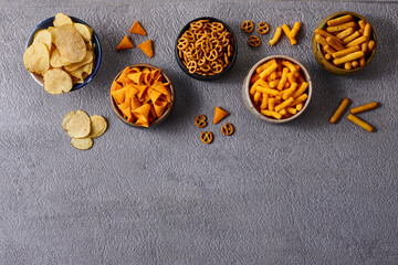 Assorted snacks in pottery bowls on grey background