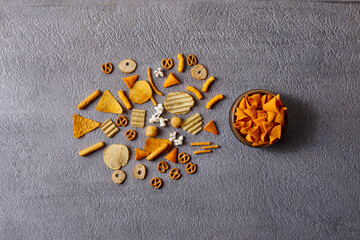 Assorted snacks in pottery bowls on grey background