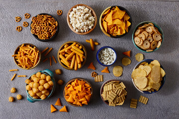 Assorted snacks in pottery bowls on grey background