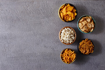 Assorted snacks in pottery bowls on grey background