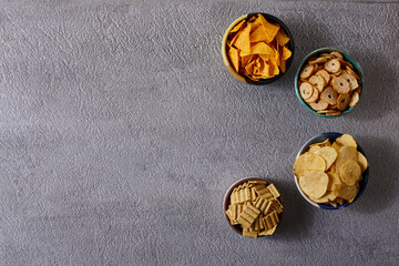 Assorted snacks in pottery bowls on grey background