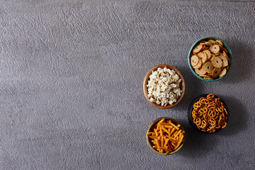 Assorted snacks in pottery bowls on grey background