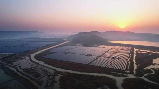 Solar power station on tidal flats at sunset with distant mountains and reflective water surfaces