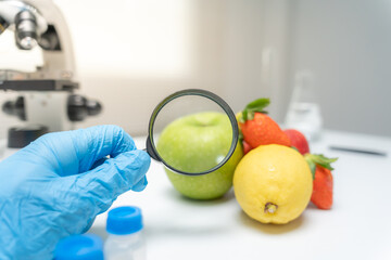 Scientist use magnifying glass to check physical occur from chemical on fruit and vegetable residues in laboratory. inspect the concentration of chemical residues, standard, find prohibited substances