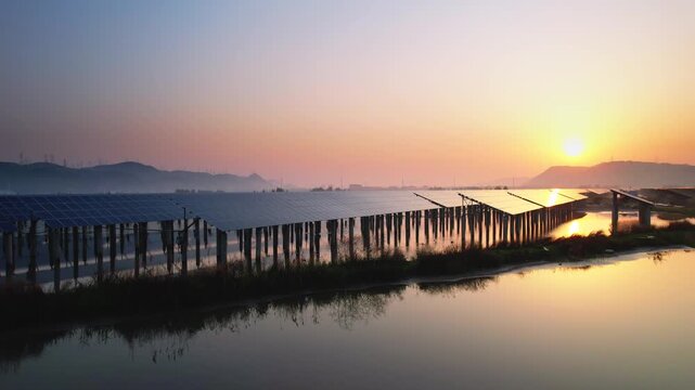 Sunset over tidal flats with fishing racks reflecting in calm water