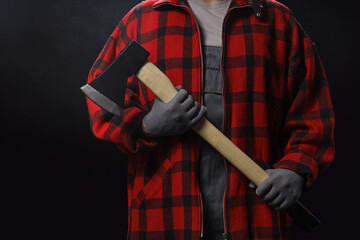 Handsome lumberjack with ax on dark background, closeup